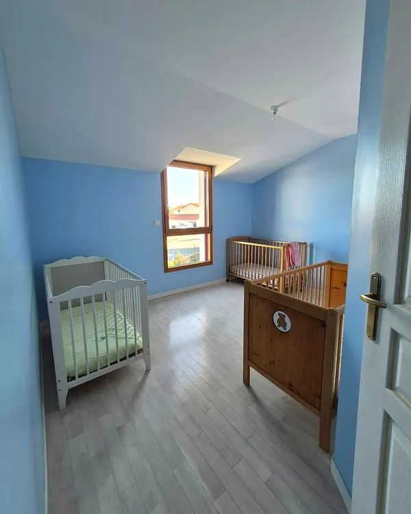 Chambre aux murs bleus avec trois lits à barreaux