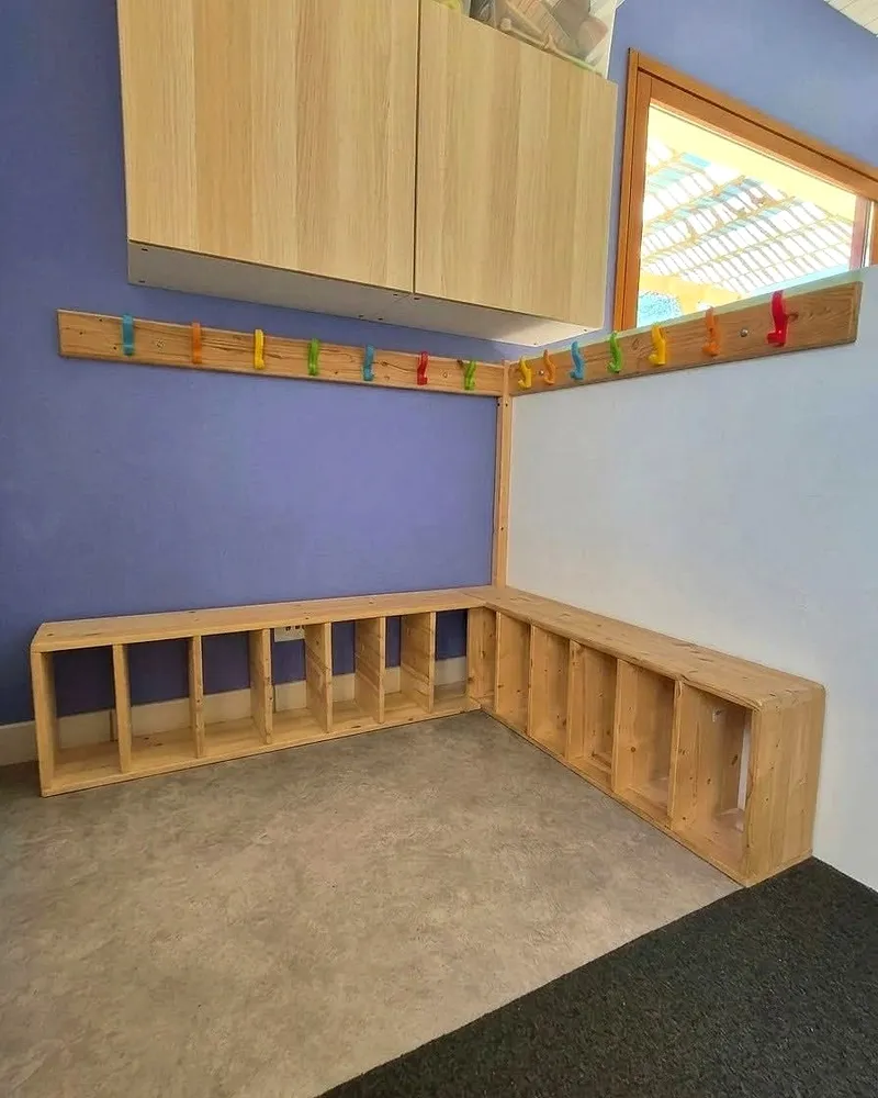 Vestiaire en bois avec des casiers bas et des porte-manteaux colorés à hauteur d'enfants
